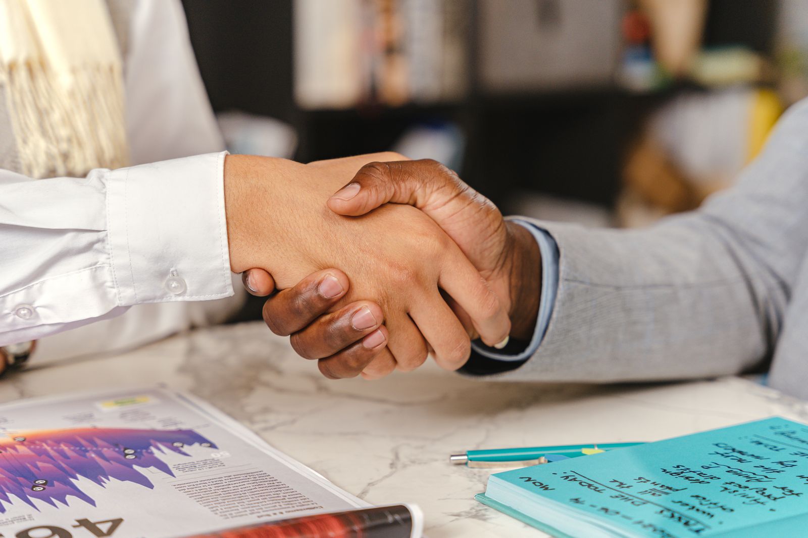 Handshake over compliance paperwork at an office desk
