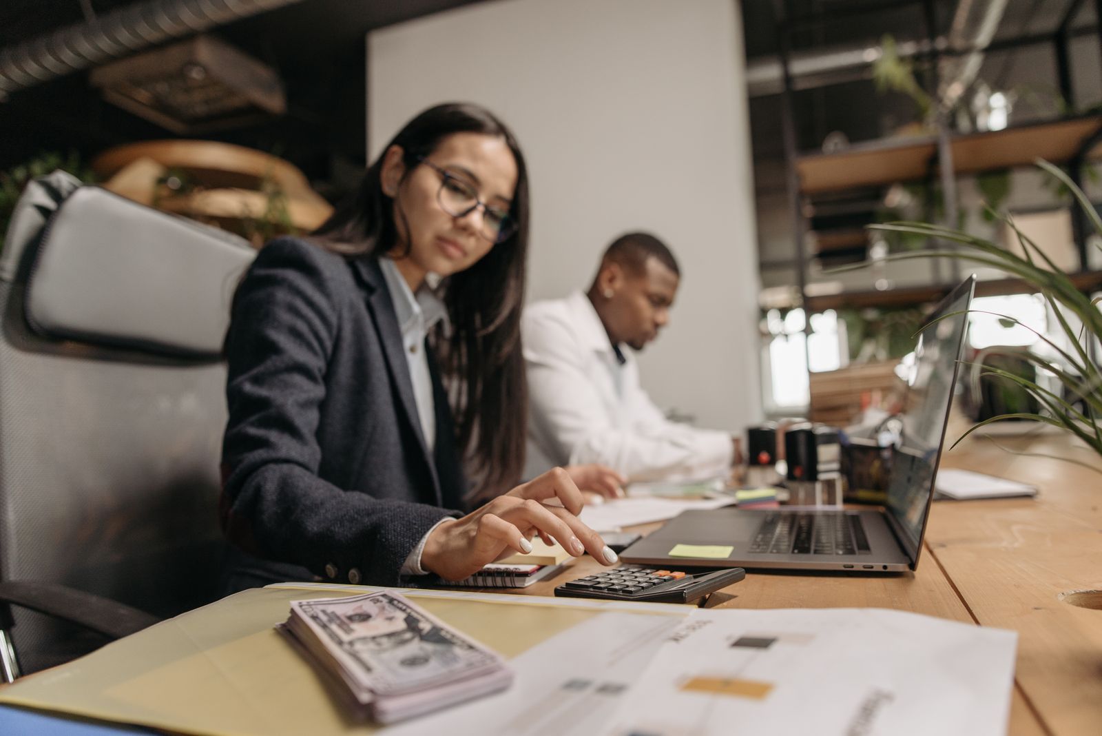 Payroll administrator working through paperwork and a calculator at a desk